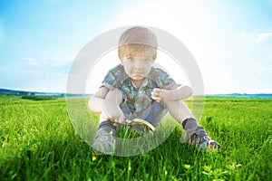 Get to know the world. Everything is incredible near you. Young boy exploring nature in a meadow with a magnifying glass