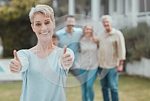 They get two thumbs up. a mature woman showing a thumbs up in the garden at home.