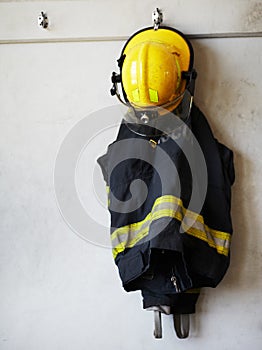 Get your gear up. Shot of a firemans uniform hanging on the wall.