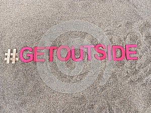 #getoutside get outside written on sand at the beach