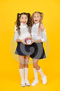Getting back to class in time. Happy little girls back to school on september 1. Small schoolchildren smiling with clock