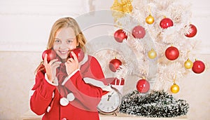 Getting child involved decorating. Girl smiling face hold balls ornaments white interior background. How to decorate