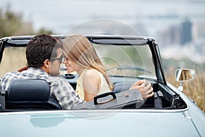 Getting close. An attractive young couple in their convertible while on a roadtrip.