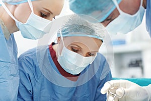 Getting a closer look. Closeup of medical surgeons at work using forceps.