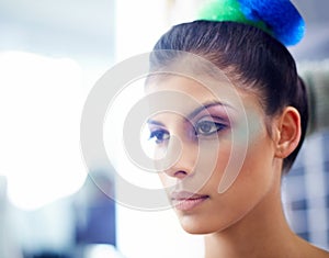 Getting creative with cosmetics. A young woman with colorful make up on her face.