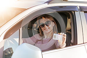 Getting a driver`s license, a beautiful driving girl shows a new driver`s license. Young woman holding driving license near open