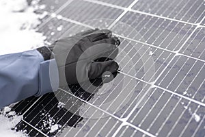 Getting electricity with solar panels in winter.Hands clear snow from solar panels.renewable energy in winter time.Solar