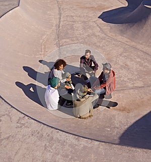 Getting a feel for the space. a group of friends hanging out in the sun at a skate park.