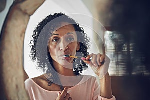 Getting fresh for the day. a mature woman looking at her reflection while brushing her teeth.