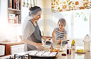 Getting her daughter enthusiastic about baking. a little girl baking with her mother in the kitchen.