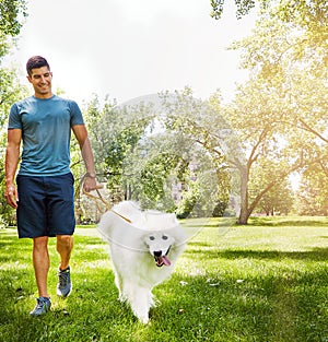 Getting his daily exercise. a handsome young man walking his dog in the park.