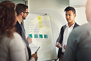 Getting his team involved in on development. Shot of a young man giving a presentation to colleagues in an office.