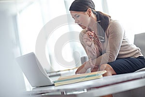 Getting the job done. pretty business woman browsing on her laptop in the office with copyspace.