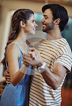 Getting lost in each others eyes. an affectionate young couple dancing in their kitchen at home.