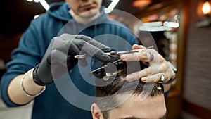Getting modern haircut. Close up shot of professional male barber making haircut for his client, working with scissors