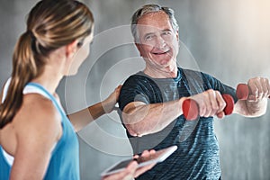 Getting older, getting fitter, getting stronger. Shot of a senior man using weights with the help of a physical