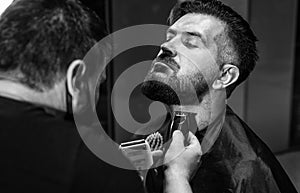 Getting perfect shape of mature bearded man getting beard haircut by hairdresser at barbershop, Designing new hairdo