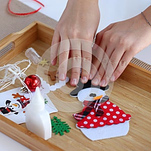 Getting ready for Christmas. Children`s hands collect Christmas tree toy Snowman. Tools for work are on the table. Getting ready