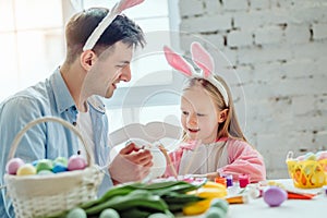 Getting ready for Easter with dad.Dad and his little daughter together have fun while preparing for Easter holidays.On the table