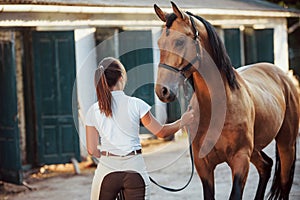 Getting ready for the ride. Horsewoman in white uniform with her horse at farm. Ready for the ride