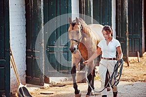 Getting ready for the ride. Horsewoman in white uniform with her horse at farm. Ready for the ride