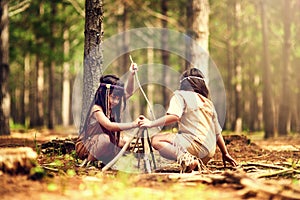 Getting ready to send some smoke signals. two little girls building a campfire while playing dressup in the woods.