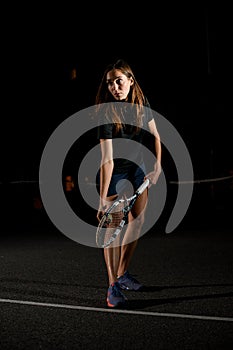 Getting ready to serve. Handsome young woman preparing to serve tennis ball. Dark background