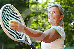 Getting ready to serve - Tennis technique. Senior woman preparing to serve a tennis ball.