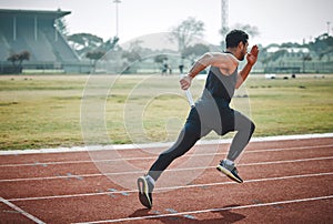 Getting the relay up and running. Full length shot of a handsome young male athlete running with a baton during a relay