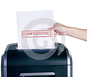 Getting rid of the evidence. Studio shot of a womans hand placing a confidential document into a shredder against a