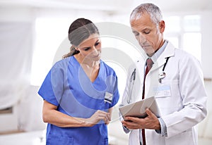 Getting a second opinion. two medical professionals looking at a digital tablet.