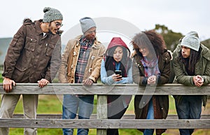 Getting that selfie onto social media, stat. a group of friends hanging out on a wooden bridge together.