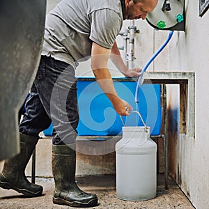 Conseguir alguno Agua su animales de granja. masculino agricultor relleno arriba una lata Agua sobre su lácteos 
