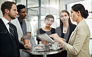 Getting their feedback. a group of businesspeople looking at a tablet in the office.