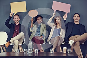 Getting their speech out there. a group of businesspeople holding up speech bubbles while waiting in line for an