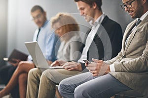 Getting through the wait for their call. Shot of a group of businesspeople waiting in line for a job interview.