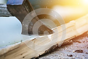 Getting wood for fire: Sharp axe cutting wood on a block. Sunlight