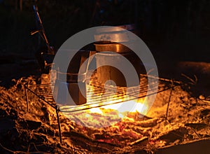 A geyser coffee machine near the fire. Picnic in nature. Camping in the mountains. Night coffee in the forest