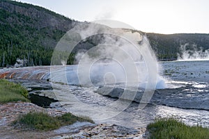 Geyser erupts in the Black Sand Basin area of Yellowstone National Park at sunset