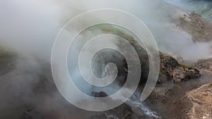 A geyser erupts on the hillside.