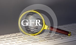 GFR - Glomerular Filtration Rate text on magnifier on a keyboard, business concept