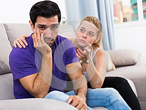 Ggirl comforting upset boyfriend on sofa