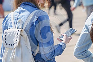 Ggirl in the denim jacket is holding a smartphone