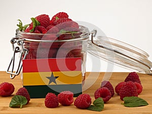 Ghanaian flag on a wooden panel with raspberries isolated on a w