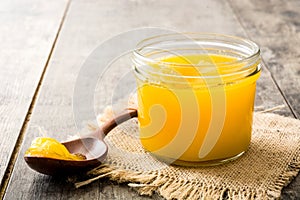 Ghee or clarified butter in jar and wooden spoon on wooden table. photo