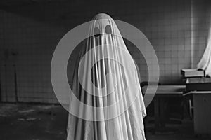 Ghost covered with a white ghost sheet in abandoned house. Halloween Concept