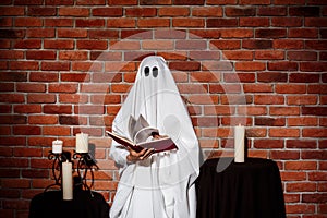 Ghost holding book over brick background. Halloween party.