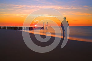 Ghost man watching a sunset on a beach