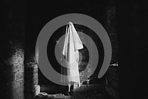 A ghost standing in an abandoned building at night. Mystery and horror. The eerie image is reminiscent of Halloween and explores