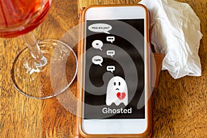 Ghosted on mobile phone on table with glass of wine and tissue, Ghosting to cut all communication